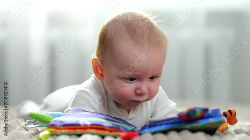Infant Explores Vibrant Textured Pages. Young Baby Investigates Soft Pages With Tabs On Rug Early. Quiet Morning Scene Showing Curious Infant Engaging With Tactile Cloth Pages Peacefully