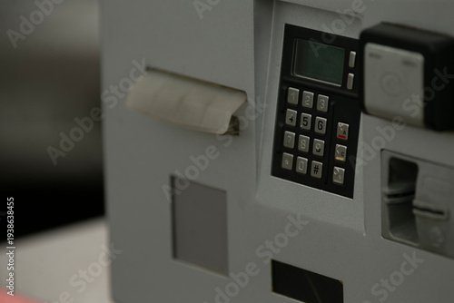 Closeup payment terminal urban parking kiosk, metal keypad and card slot with numeric display, contactless logo, scuffed edges, ambient street light,