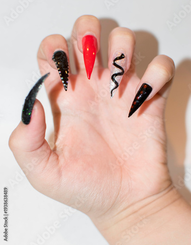 Hand with Long Stiletto Nails Featuring Diverse Creative Art