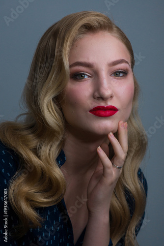 Close-up profile of a stylish blonde woman with glamorous wavy hair, red lipstick, and shimmering eyeshadow