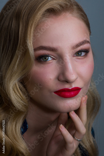 Close-up profile of a stylish blonde woman with glamorous wavy hair, red lipstick, and shimmering eyeshadow