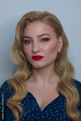 Portrait of a beautiful blonde woman with elegant wavy hair, professional makeup, and red lipstick