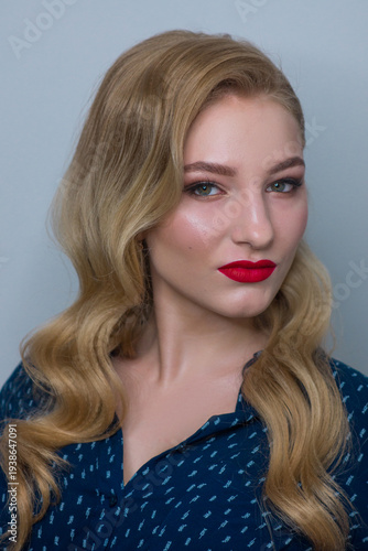 Portrait of a beautiful blonde woman with elegant wavy hair, professional makeup, and red lipstick
