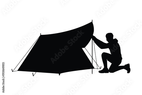 Silhouette of a person setting up a tent outdoors