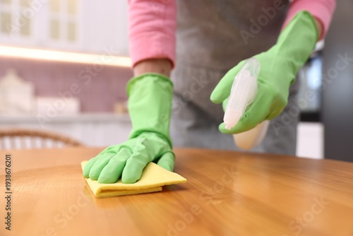 Принти на полотні Woman using cleaning product while wiping wooden table with rag indoors, closeup