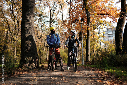Smiling couple cycling together on autumn forest path. Active lifestyle and outdoor recreation concept.