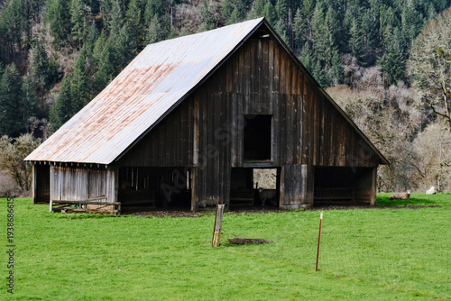 Old abandoned barn with metal roof decaying in a field