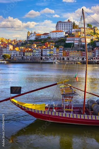 Old town of Porto, Portugal. Antique boat with port wine barrels on the water Douro River. Sunny day over silhouettes skyline roofs houses along river.
