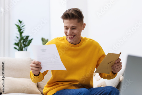 Billede på lærred Happy man with acceptance letter from university on sofa at home