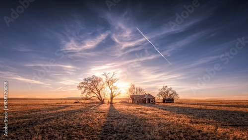 Old abandoned wooden farmhouse on the prairie at sunset. Colorful clouds float silently in the sky. 