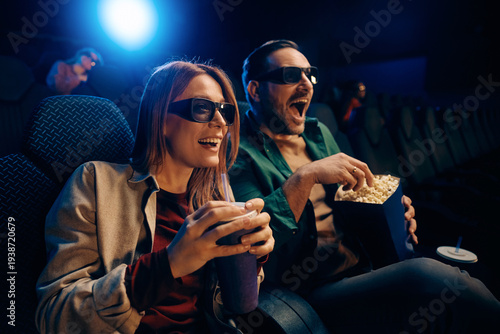 Excited couple enjoying in 3D film screening at cinema.