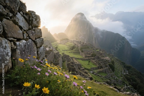 Sunrise over Machu Picchu with ancient stone ruins and wildflowers in the foreground