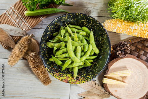 A bowl of boiled edamame beans presented in a rustic setting. The simple composition highlights healthy plant based snacks suitable for appetizer and side dish menus.