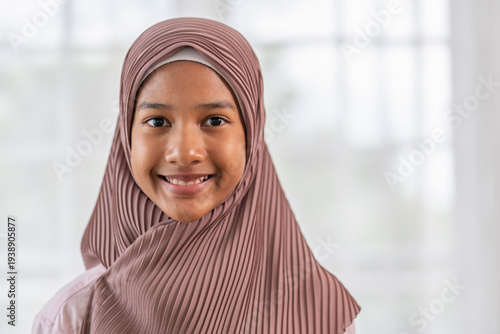Bild auf Leinwand A smiling muslim teenage girl wearing a beautiful pleated dusty pink hijab, look