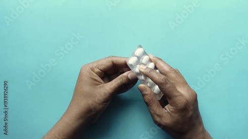 Close up of hands holding blister pack of white oval pills