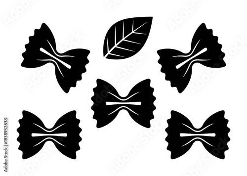 Black Farfalle Pasta Shapes and a Leaf on a White Background