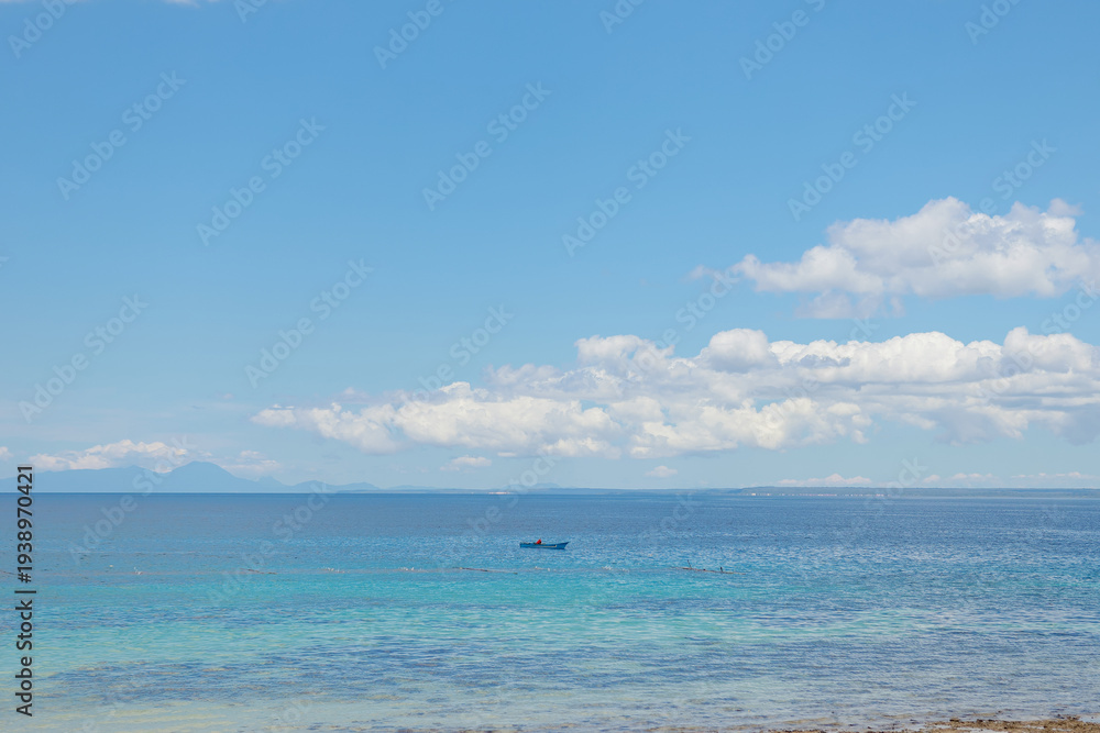 Fototapeta premium beautiful view of the beach and tropical blue sea during the day with the background of islands and clouds on daylight. beautiful view suitable for wallpaper or background