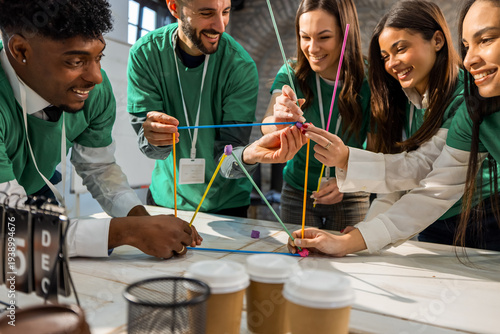 Happy diverse group of people recycling plastic straws into a creative structure.