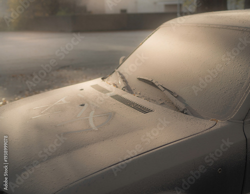 An old abandoned vintage car sitting on a rainy street with wet pavement and a quiet atmosphere
