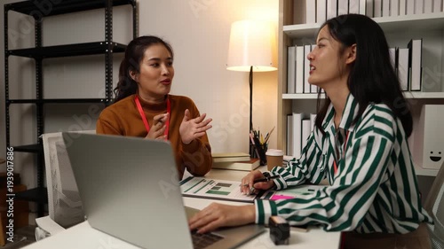 Two businesswomen discussing startup ideas and reviewing documents during a meeting in modern office, representing teamwork, business planning and collaboration in a startup company.
