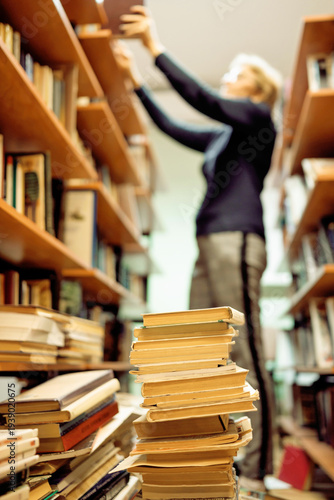 A female librarian arranges books on the shelves in the library.