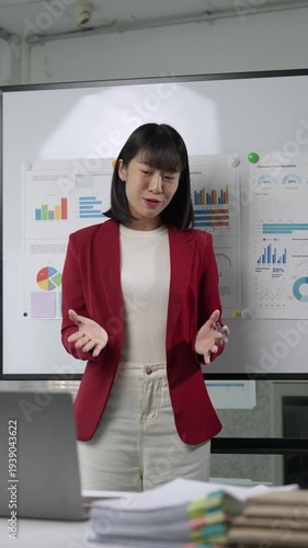 Asian businesswoman presenting financial data on a whiteboard