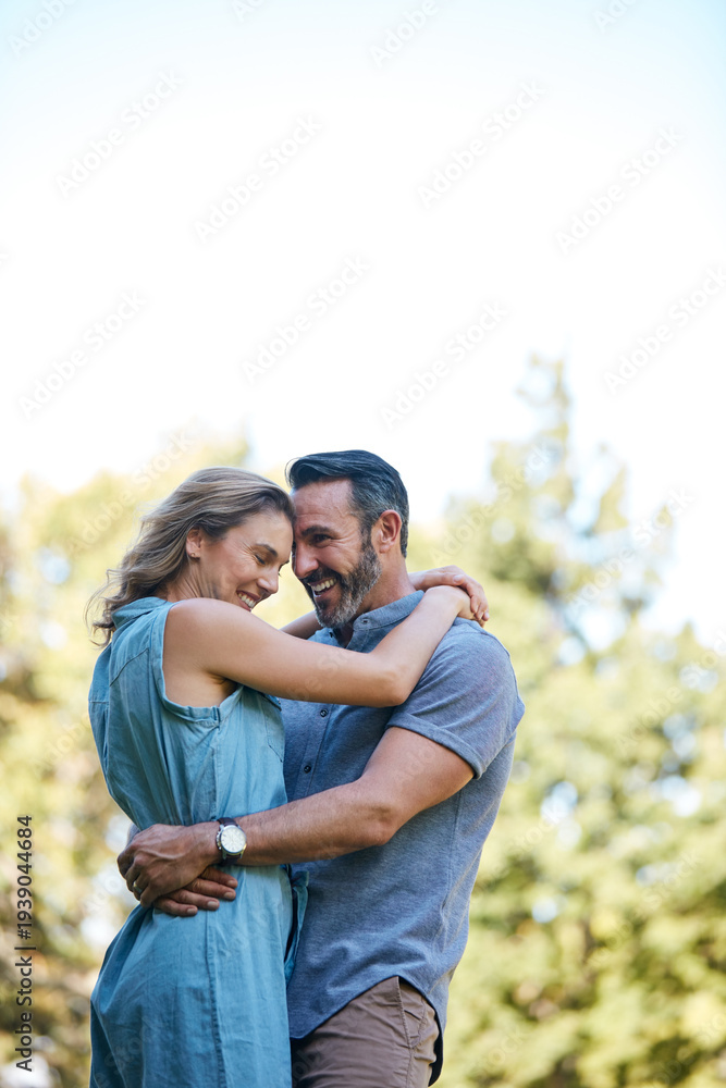 Fototapeta premium Happy, hug and couple in nature for love, care and bonding in marriage at park by space. Smile, outdoor and man embracing woman for trust, safety and connection in relationship at countryside.