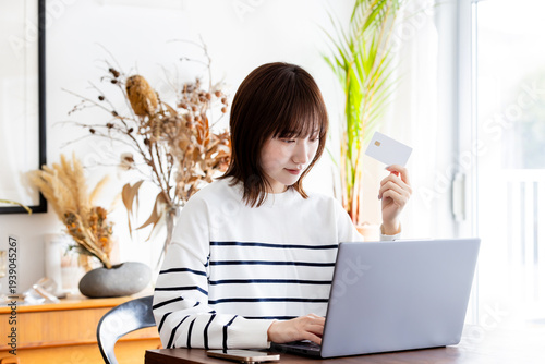 リビングでネットショッピングするカードを持った若い主婦