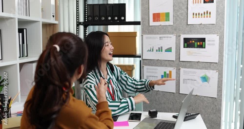 Two businesswomen discussing startup ideas and reviewing documents during a meeting in modern office, representing teamwork, business planning and collaboration in a startup company.