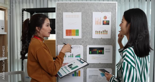 Two businesswomen discussing startup ideas and reviewing documents during a meeting in modern office, representing teamwork, business planning and collaboration in a startup company.