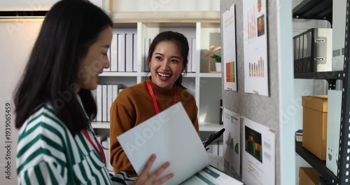Two businesswomen discussing startup ideas and reviewing documents during a meeting in modern office, representing teamwork, business planning and collaboration in a startup company.