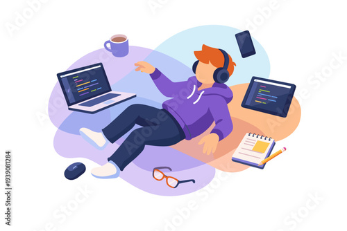 Young programmer wearing headphones working on laptop and tablet.