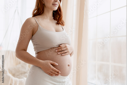 Pregnant woman touching and caressing her baby bump feeling motherhood and expectancy