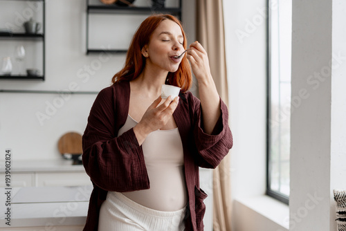 Konstfotografi Pregnant woman enjoying healthy yogurt snack in kitchen, focusing on nutrition