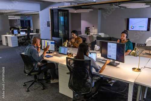 Quadro su tela Diverse coworkers using headsets and monitors, collaborating at open-plan office