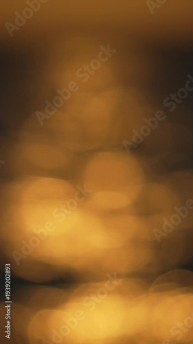Golden water bokeh, abstract shimmering light reflections create a peaceful and serene backdrop. Vertical video.