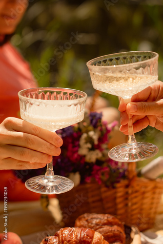 summer vacation picnic with friends clinking glasses with champagne outdoors