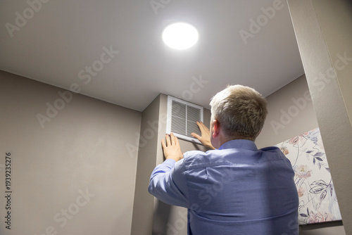A person cleaning with a brush an HVAC return air vent grille and duct. Maintenance