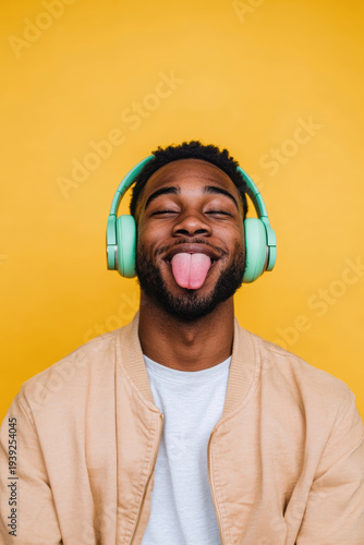 Young man enjoying music with headphones on a bright yellow background
