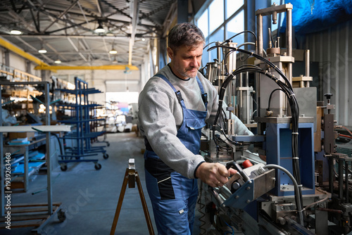 Man worker assembling PVC windows using advanced machinery at plant