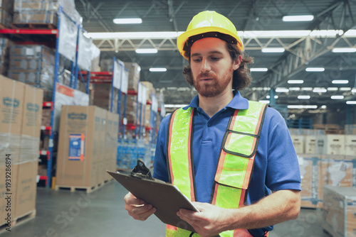 Photos Man wearing helmet and reflective vest is easily noticeable while inspecting warehouse in a Southeast Asian logistics system