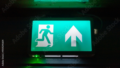 Emergency exit sign. Green fire exit sign closeup