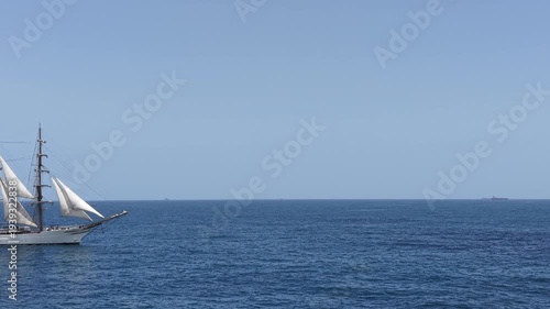 Aerial view of a three-masted sailing ship with sails and a large Brazilian flag on the stern sailing in the Atlantic Ocean. The training ship of the Brazilian Navy.