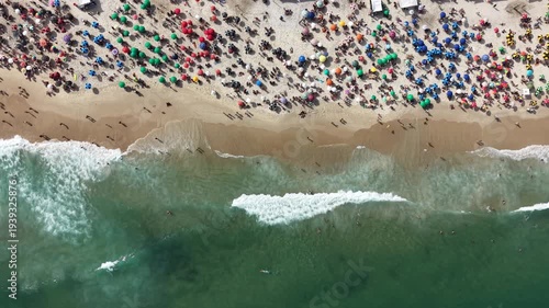 Rio de Janeiro, Brazil, aerial view of Copacabana Beach showing colourful umbrellas and people bathing in the ocean on a summer day. Tropical travel and vacation concept.