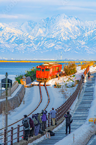 Japan - February 5, 2026 : JR Himi Line Train with Tateyama  Mountain Range of Japan Alps Background in winter, Amaharashi Kaigan Coastline, Takaoka City, Toyama, Japan
