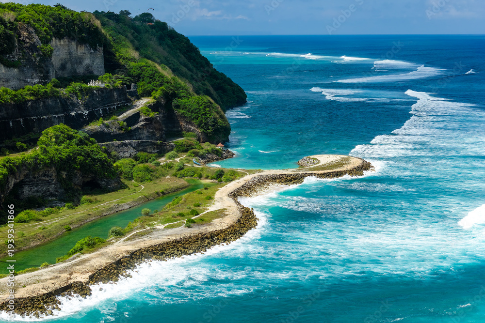Fototapeta premium Aerial drone view of a scenic tropical coastline featuring lush cliffs and bright ocean