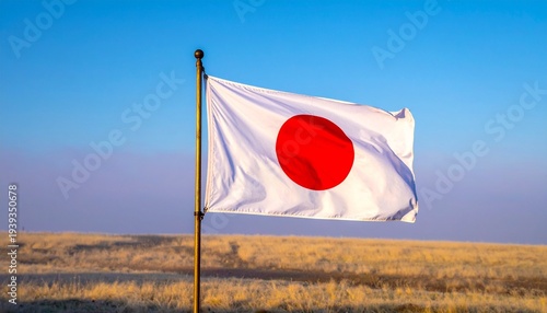 Wallpaper Mural "Japanese flag with red sun disc flying on outdoor flagpole against grassy field and clear blue sky." Torontodigital.ca