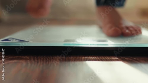 Close-up of male bare feet stepping on digital scales to check weight.