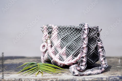 Handmade woven crossbody bag with palm leaf on stone surface