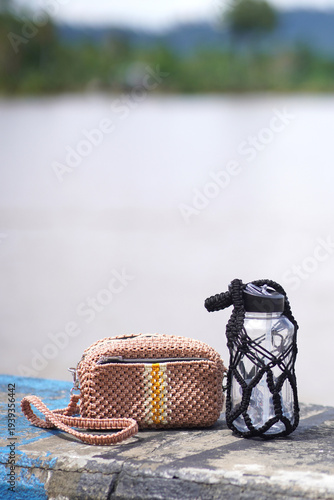 Crochet bag and water bottle on rustic surface outdoors